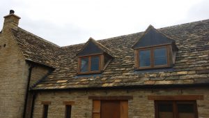 Cotswold natural stone tiles and vertical lead cladding on front of dormers